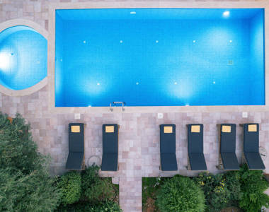 Vederi Estate Villa Melpomeni top-down view of the lit up pools and sunbeds