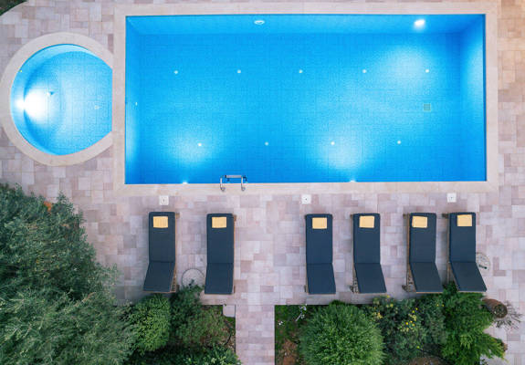 Vederi Estate Villa Melpomeni top-down view of the lit up pools and sunbeds