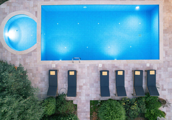 Vederi Estate Villa Melpomeni top-down view of the lit up pools and sunbeds