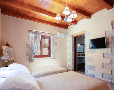 Vederi Estate Villa Melpomeni bedroom with two single beds and a wall mounted television