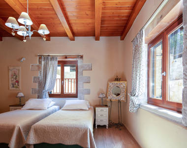 Vederi Estate Villa Melpomeni bedroom with two single beds, bedside tables, decorations and amenities