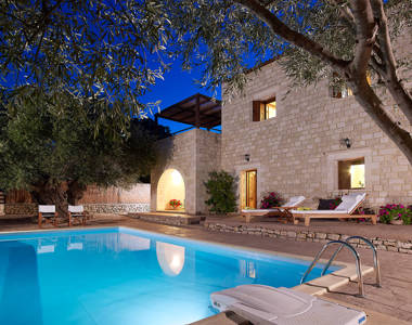 Vederi Estate Villa Kyveli pool, sunbeds and villa exterior lit up at dusk