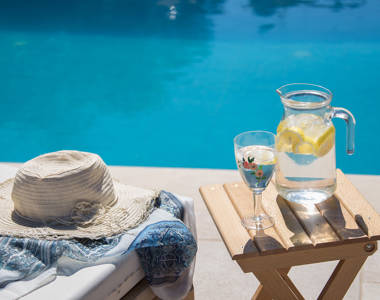 Vederi Estate Villa Melpomeni poolside small table with a jug and a glass of water with lemon slices in them