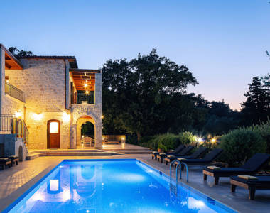 Vederi Estate Villa Melpomeni villa exterior and pool lit up at dusk