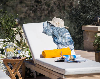 Vederi Estate Villa Melpomeni decorated sunbed and a jug with a glass of water on the table next to the sunbed