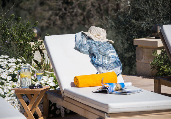 Vederi Estate Villa Melpomeni decorated sunbed and a jug with a glass of water on the table next to the sunbed